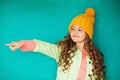 Little lady in yellow woolen cap point on something