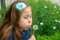 Little latina girl in garden blowing on dandelion