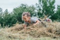 Little laughing girl 3-4 years old jumps and plays in hay stack, on background of trees Royalty Free Stock Photo