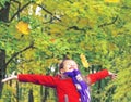 Little laughing pretty girl in red coat throws yellow leaves in autumn park Royalty Free Stock Photo