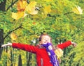 Little laughing pretty girl in red coat throws yellow leaves in autumn park Royalty Free Stock Photo