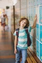 Little learner standing near lockers in school hallway Royalty Free Stock Photo