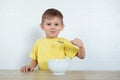 Little left-handed boy in a yellow T-shirt eating fruit salad and smiling. Children healthy food concept. Nutrition products.