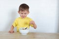 Little left-handed boy in a yellow T-shirt eating fruit salad and smiling. Children healthy food concept. Nutrition products.