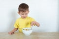 Little left-handed boy in a yellow T-shirt eating fruit salad and smiling. Children healthy food concept. Nutrition products.