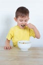 Little left-handed boy in a yellow T-shirt eating fruit salad and smiling. Children healthy food concept. Nutrition