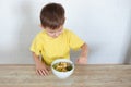 Little left-handed boy in a yellow T-shirt eating fruit salad and smiling. Children healthy food concept. Nutrition products.