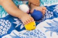 Little legs of a baby girl sitting on a beach towel and playing with rubber toys at summer time Royalty Free Stock Photo