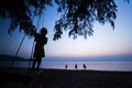 A little local girl playing on the swing on the beach at sunset Royalty Free Stock Photo