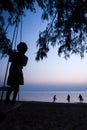 A little local girl playing on the swing on the beach at sunset Royalty Free Stock Photo