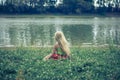 Little lonely girl sitting in the grass by the river Royalty Free Stock Photo