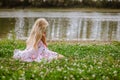 Little lonely girl sitting in the grass by the river Royalty Free Stock Photo