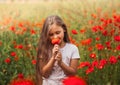 Little longhaired girl posing at field of poppies with on summer sun