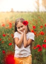 Little longhaired girl  posing at field of poppies with  on summer sun. Vertical Royalty Free Stock Photo