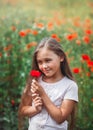 Little longhaired girl  posing at field of poppies with  on summer sun. Vertical Royalty Free Stock Photo