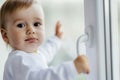 Little, lost in thoughts, and little boy sitting by the window and thinking and waiting for something Royalty Free Stock Photo