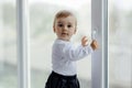 Little, lost in thoughts, and little boy sitting by the window and thinking and waiting for something Royalty Free Stock Photo