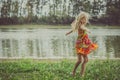 Little lovely girl dancing in the grass by the river Royalty Free Stock Photo