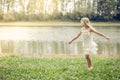 Little lovely girl dancing in the grass by the river Royalty Free Stock Photo