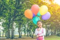 Little lovely girl holding a colorful ballons smiling in the park. Girls has a happy holiday Royalty Free Stock Photo