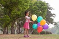 Little lovely girl holding a colorful ballons smiling in the park. Girls has a happy holiday Royalty Free Stock Photo