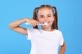 Little lovely girl with two cute ponytails posing with toothbrush and toothpaste on it