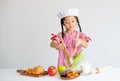 Little lovely girl use ladle to mix salad in glass bowl on table and she look enjoy with this activity