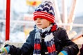 Little lovely kid boy having fun on ferris wheel on traditional German Christmas market during strong snowfall. Happy