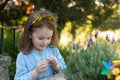 A little lovely modest girl with a crown happy birthday on her head and in a denim blue dress holds a lavender flower in her hands