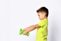 Little male in yellow t-shirt and denim shorts. He smiling, lifting green dumbbell, posing isolated on white studio background Royalty Free Stock Photo