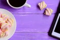 Little marshmallow on a plate, a cup of coffee, tablet on a wooden background with copy space for text. Female workplace