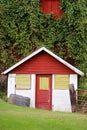 Little Milk House Structure with Old Door Attached to Large Red Dairy Barn Covered in Green Vines Royalty Free Stock Photo