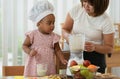 Little mixed race child girl, African and Asian, and mother making healthy fruits smoothie with blender together from apple, Royalty Free Stock Photo