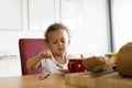 Little mixed-race girl at home having breakfast.