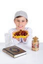 Little Muslim kid presenting a dish of dates in Ramadan