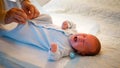 Little newborn baby getting dressed and sucking pacifier on bed at night. caring mother changing clothes of her baby son Royalty Free Stock Photo