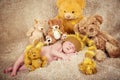 Little newborn baby in a knitted cap sleeping near teddy bears toys.