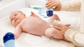 Little newborn baby lying on changing table while mother changing diaper and applying talc on soft skin. Concept of