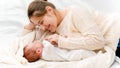 Little newborn baby and mother in wool sweater lying on bed at morning Royalty Free Stock Photo