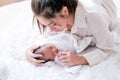 Little newborn baby sleep and hold mother finger in her hand on white bed with morning light