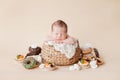 A little newborn baby sleeps in a straw basket on a beige background, there are many donuts, cakes and sweets