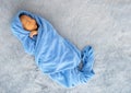 Little newborn baby is wrapped with blue towel and the baby is sleeping on gray carpet Royalty Free Stock Photo