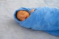 Little newborn baby is wrapped with blue towel and the baby is sleeping on gray carpet Royalty Free Stock Photo