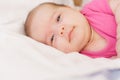 Little newborn lying on her stomach on a white bed. The newborn is awake looking around in the room. Newborn baby in a Royalty Free Stock Photo
