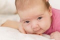 Little newborn lying on her stomach on a white bed. The newborn is awake looking around in the room. Newborn baby in a Royalty Free Stock Photo