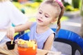 Little nice girl eating rench fries with sauce at street cafe outside. Royalty Free Stock Photo