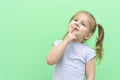 Little nice girl 4 years old in a blue T-shirt on a green background in a blue T-shirt emotionally thought, index finger near lips Royalty Free Stock Photo