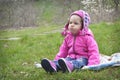 Little offended girl sitting on the spring meadow.