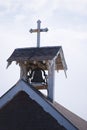 Little old bell tower with cross on roof of provincial wooden ch