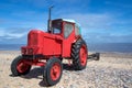 Little old red diesel tractor on the beach. Royalty Free Stock Photo